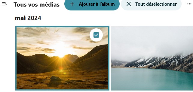Capture d'écran d'une partie de la page principale de l'application. On voit en haut de gauche à droite "Tous vos médias", ""+ Ajouter à l'album" et "Tout désélectionner". Dessous "mai 2024". Dessous 2 images l'une représentant un paysage avec des montagnes derrières lesquelles se couche le soleil. Dans le coin droit de cette image en haut il y a une case qui est cochée, entourée d'un cercle blanc. La seconde image à droite de la première représente un lac au bas des montagnes dont les sommets sont cachés par la brume.