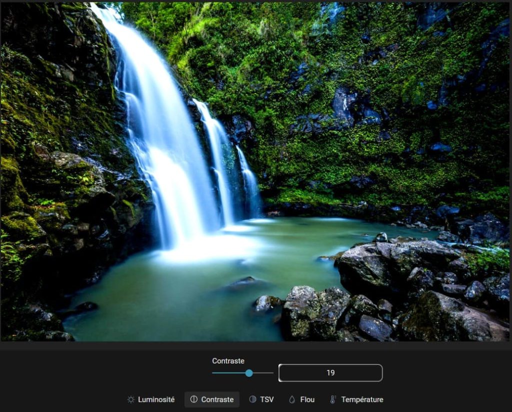 Capture d'écran d'une image (une cascade) ouverte dans la partie "Réglages fins", "Contraste" des modifications. dans la partie basse le paramètre pour le contraste est un petit rond à tirer vers la droite ou la gauche pour modifier le contraste. Sur la droite de cette réglette, un champ avec un chiffre indiquant le taux de contraste. En-dessous il y a 5 items, "Luminosité", "Contraste", "TSV", "Flou" et "Température".